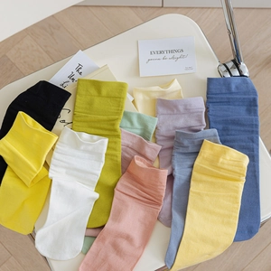 Flat lay of colorful mid-calf cotton socks in various pastel shades for women