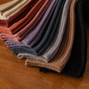 Close-up of ribbed knit cotton crew socks in various warm earth tone colors on wood