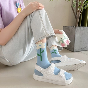 Dettaglio di calze in cotone azzurro con grandi motivi a tulipano bianco da donna