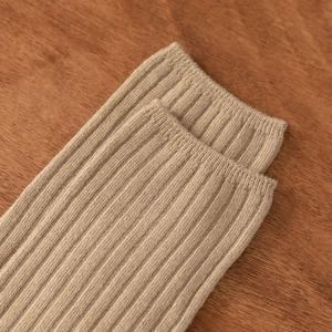 Detail view of khaki ribbed knit cotton socks with reinforced cuffs on a wooden surface