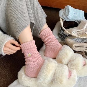 Detailed close-up of pink wool socks with cute bow embroidery and scalloped edges