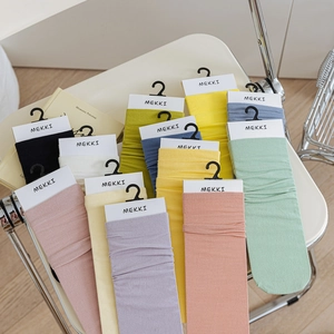 Colorful mid-calf velvet socks in pastel shades displayed on a chair and wood floor