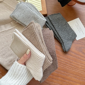 Detail of ribbed knit wool blend socks in various earth tones on a warm wooden background