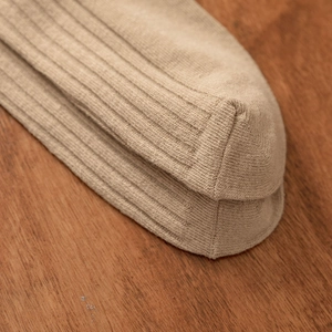 Macro shot of reinforced toe seam and ribbed texture on beige cotton crew socks