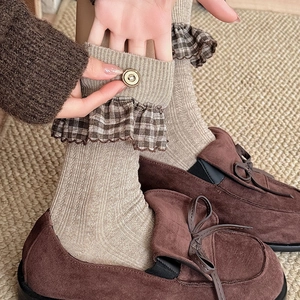 Detail of knit crew socks with plaid ruffle trim and button accent in beige
