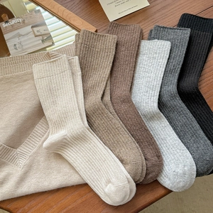 Close-up of ribbed wool blend mid-calf socks in warm earthy tones on wood surface