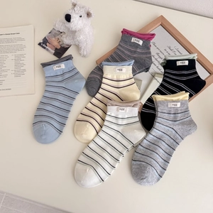 Set of 6 colorful striped combed cotton socks with minimalist egg label on light desk