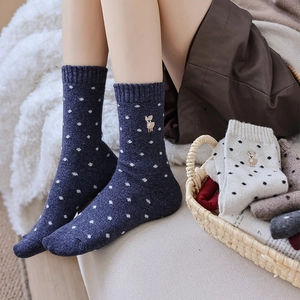 Detailed view of thick navy wool socks featuring white polka dots and deer embroidery