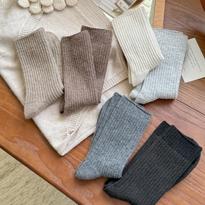 Vertical ribbed wool socks in neutral tones on a cozy wooden tabletop background