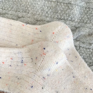 Detailed macro view of cream-colored confetti wool socks with ribbed texture and colorful dots