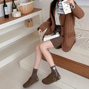 Nahaufnahme brauner Socken mit Rüschenkante und Vintage-Mules aus Wildleder
