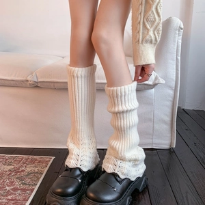Détail de jambières en tricot blanc avec motifs ajourés et finitions en maille côtelée