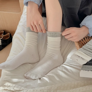 Women's cream white ribbed mid-calf socks with contrast trim shown in a cozy home setting