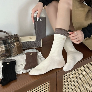 Detail of striped cuffs and button decor on ribbed cotton mid-calf socks for women