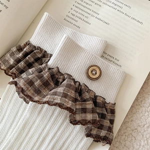 Detail of vintage-style knit socks with plaid ruffled cuffs and a wooden button accent