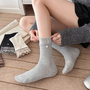 Détail de chaussettes en tricot avec bordure à volants à carreaux et boutons floraux