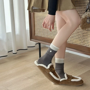 Detail of warm brown mule slippers with white faux fur lining and grey ribbed cotton socks