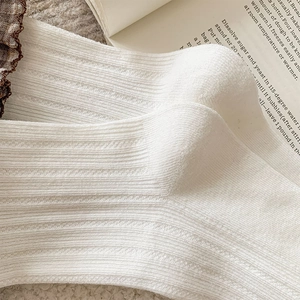 Close-up of cream white ribbed knit socks with wavy lace edges for a vintage look