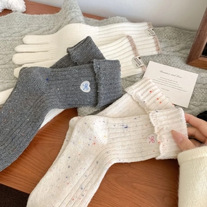 Close-up of wool socks with heart bow embroidery and colorful polka dot knit textures