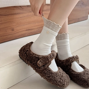 Détail de chaussettes mi-mollet blanches côtelées avec bordure en dentelle à carreaux