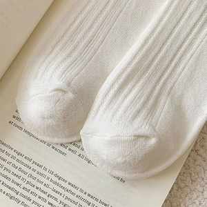 Close-up of white ribbed knit cotton socks showing detailed vertical stripe texture