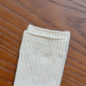 Close-up of cream wool blend socks with vertical rib knit and rolled cuff detail