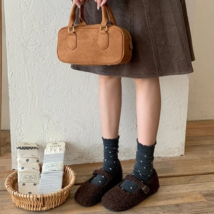Detail of dark brown Mary Jane shoes paired with gray polka dot wool socks in a cozy setting