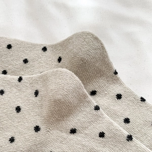 Macro view of beige wool socks with black polka dots and soft knitted texture details