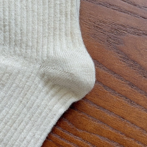 Detailed macro shot of ribbed wool blend texture on minimalist beige crew socks