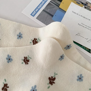Detail von cremeweißen Rippstrümpfen mit blau-brauner Stickerei für Damen