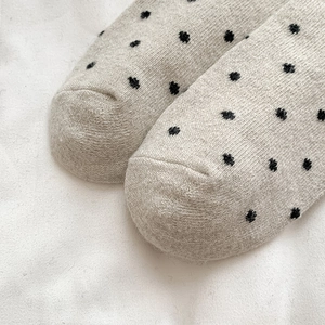 Detailed macro view of polka dot pattern on warm oatmeal wool knit socks with thick texture