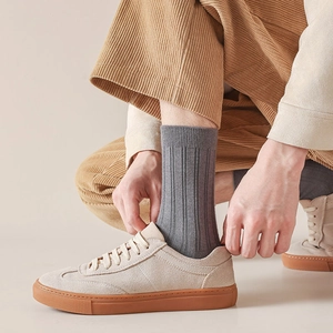 Close-up of grey ribbed business socks worn with beige suede shoes and corduroy pants