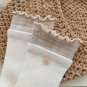Détail de chaussettes à volants avec bordure à carreaux et bouton fleur style japonais