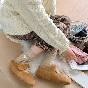 Detailed view of beige polka dot wool socks with blue bow embroidery and brown Mary Jane shoes