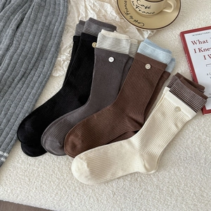 Detail of ribbed knit mid-tube socks with striped trim and button accent in four colors