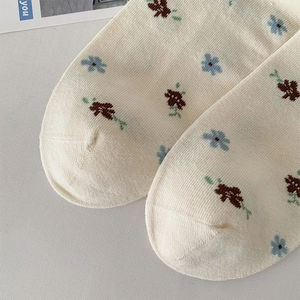 Nahaufnahme der Blumenstickerei auf cremefarbenen Baumwollsocken mit Strickstreifen