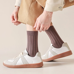 Detail of dark brown ribbed cotton crew socks paired with white sneakers and corduroy pants