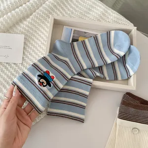 Detailaufnahme von hellblau gestreiften Baumwollsocken mit bunter Pinguin-Stickerei an der Seite