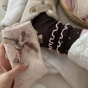 Detail of wool socks featuring cute brown bows and pink ruffle edges in cozy knit style