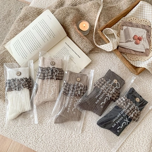 Detail of 5-pack retro plaid lace cuff socks with wooden buttons in clear packaging