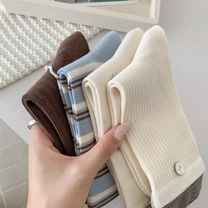 Nahaufnahme von Baumwollsocken mit Retro-Streifen und Knopf-Details in warmen Neutraltönen