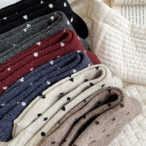 Close-up of stacked colorful polka dot wool socks with ribbed texture in various autumn shades