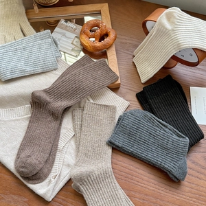 Close-up of thick ribbed wool socks in neutral colors displayed on a rustic wooden table