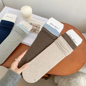 Close-up of four colored ribbed crew socks with brand packaging on a wooden table