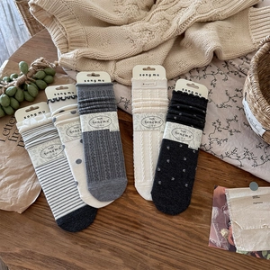 Flat lay of five retro wool blend socks with dots and stripes on dark wood surface