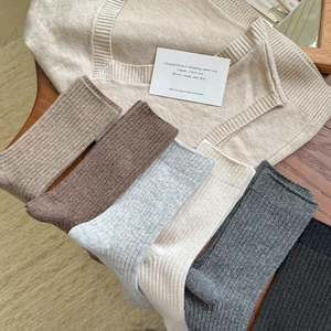 Detail of assorted ribbed wool socks in earth tones arranged on a wooden table for autumn