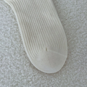 Detailed close-up of cream ribbed knit sock toe with high-quality stitching texture