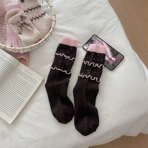 Detail of wool socks with pink ruffled edges, polka dots and cute bow design