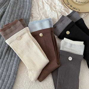 Detail of ribbed knit socks with striped cuffs and decorative buttons in various colors