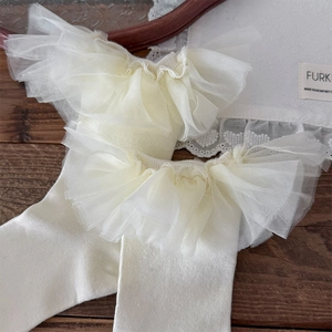 Détail de chaussettes mi-bas style Lolita avec dentelle en tulle et texture tricotée
